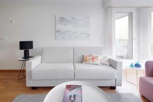 ein weißes Wohnzimmer mit einer Couch und einem Tisch in der Unterkunft Playa de Ondarreta 2 by FeelFree Rentals in San Sebastián