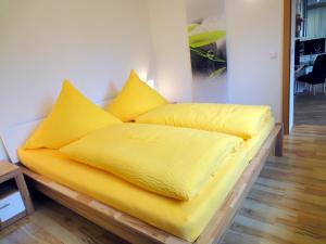 Una cama amarilla con almohadas amarillas encima. en Ferienwohnung Ginkgo, en Dresden