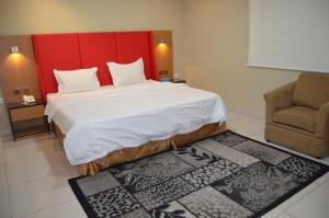 a bedroom with a large bed with a red headboard and a chair at اجنحة النرجس الفندقية in Al Khobar +65 photos