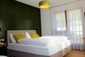 um quarto com uma cama com lençóis brancos e almofadas amarelas em Gartenresidence Stephanie by Hotel Rotwand em Laives