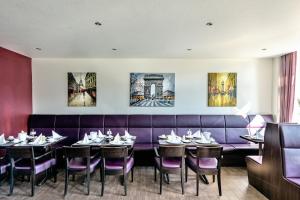 a dining room with tables and a purple couch at Hotel Monopol in Gelsenkirchen