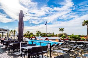 a pool with tables and chairs and a umbrella at Cumberland Hotel - OCEANA COLLECTION in Bournemouth