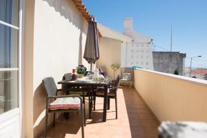 a balcony with a table and chairs and an umbrella at Apartamento Remos in Sesimbra