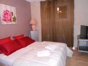 a bedroom with a white bed with red pillows and a television at Maison Monica Exeptionnel-Jardin paysage ZEN in Coursan