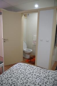 a bedroom with a bed and a bathroom with a toilet at Casinha da Calçada in Ponte de Lima