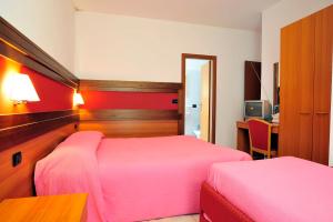 Val Masino的住宿－Hotel Ristorante Sasso Remenno，一间卧室配有两张床、一张桌子和一台电视。