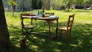 uma mesa de piquenique e um cão sentado ao lado de uma mesa e cadeiras em La Fromagerie em Saint-Martin-le-Vieux