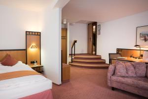 ein Hotelzimmer mit einem Bett, einer Couch und einer Treppe in der Unterkunft Hotel Schere in Northeim
