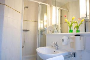 a bathroom with a sink, mirror, and tub at Hotel Schere in Northeim