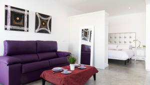 a living room with a purple couch and a bed at Apartamentos Turísticos Córdoba Califal in Córdoba