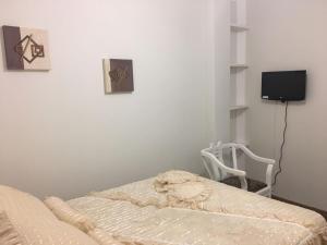 a bedroom with a bed and a chair and a tv at Residencias JAC in Paraguaçu Paulista