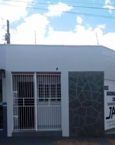 a white building with a door and a sign on it at Residencias JAC in Paraguaçu Paulista