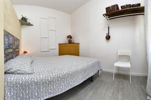 a white bedroom with a bed and a chair at Le Terrazze di Angela in Marina di Ragusa