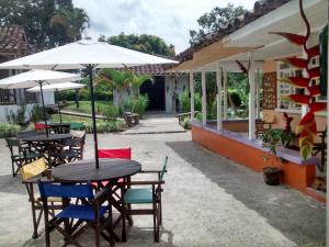eine Außenterrasse mit Tischen, Stühlen und Sonnenschirmen in der Unterkunft Secretos del Carriel Finca Cafetera in Quimbaya
