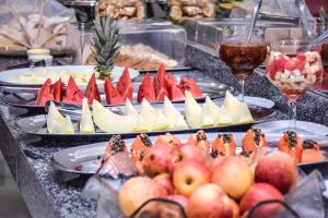 un buffet de comida con manzanas y fruta en los platos en Prime Hotel, en Feira de Santana