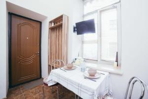 リヴィウにあるStudio Apartment Cuteのダイニングルーム(椅子と白いテーブル、窓付)