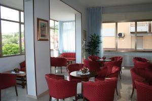 un restaurante con sillas rojas, mesas y ventanas en Albergo Esperia, en Tabiano