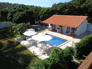 una casa y una piscina con mesas y sillas en Prima Graça, en Búzios