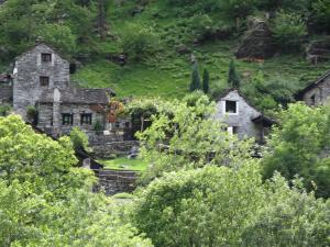 una vieja casa de piedra en una colina con árboles en Hotel Arcadia en Ascona
