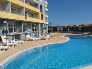 a swimming pool with chairs and umbrellas next to a hotel at Apartment Crystal Beach in Nesebar