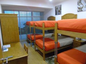 um quarto com 3 beliches com lençóis laranja em Marficas Hostel em Urzelina