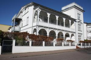un bâtiment blanc avec une clôture devant dans l'établissement Villa Concordia Apartment Hiddensee, à Binz