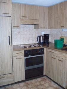 a kitchen with wooden cabinets and a stove top oven at B&B Härihof in Grüsch