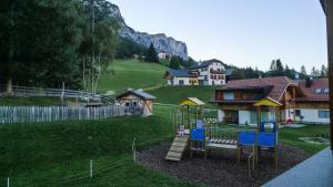 einen Spielplatz in einem Hof mit einem Haus in der Unterkunft Ciasa Odlina in Stern