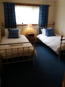 two beds in a room with a window at House for Groups & Contractors Kilmarnock in Kilmarnock