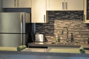 a kitchen with a sink and a stainless steel refrigerator at Nature's Door Guest Suite in Port Moody