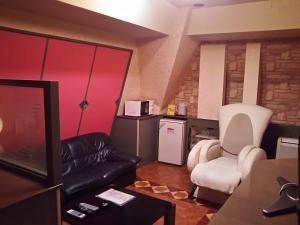 a living room with a black leather couch and white chairs at Hotel Sting in Tokyo