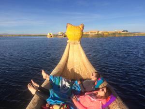people sitting on top of a boat on a body of water at UROS TITICACA LODGE Puno Peru in Puno