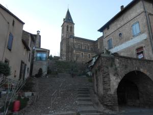 an old stone building with a church in the background at Chambre d'hôtes des Monts in Saint-Izaire
