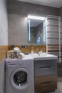 a bathroom with a washing machine and a sink at Apartamenty Galeria Jordanowska in Jordanów