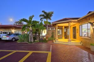 a house with cars parked in a parking lot at Gecko Inn in Richards Bay