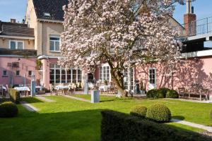 a magnolia tree in a park in front of a building at Hotel Recour in Poperinge
