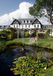 a pond in front of a house with a fountain at Ilsington Country House Hotel & Spa in Ilsington