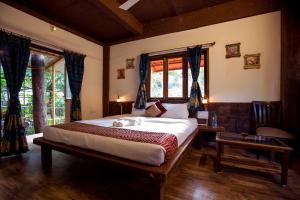 a bedroom with a large bed in a room with windows at Kaular Atithis Grand Kokan Resort in Ganpatipule