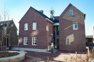 a large red brick building with a clock tower at Maison Village in Noorbeek