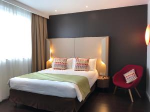 a bedroom with a large bed and a red chair at Campanile Shanghai Bund Hotel in Shanghai