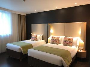 a hotel room with two beds and a window at Campanile Shanghai Bund Hotel in Shanghai