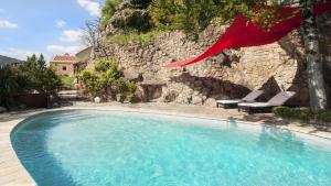 a swimming pool with two lounge chairs and a red flag at Le Colombier Saint-Véran in La Roque-Sainte-Marguerite