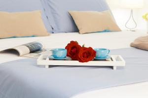 taca z różą i dwa kubki na łóżku w obiekcie Appartamenti Rosa Dei Venti w Trapani