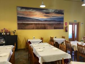 a dining room with white tables and chairs and a painting at Mirador El Silo in Bello