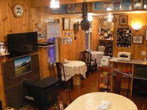 a room with wooden walls and tables and a television at Lodge Cowbell in Kutchan