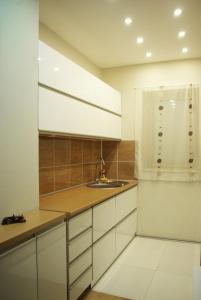 a kitchen with white cabinets and a sink at Square Studio Apartment in Niš