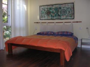 uma cama com um cobertor laranja e almofadas num quarto em b&b undici em Cervia