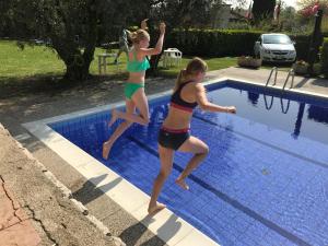 two young girls jumping into a swimming pool at Holidays Residence in Lazise