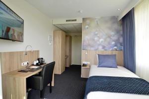 een hotelkamer met een bed en een bureau en een bed en een bureau bij Hotel De Zoete Inval Haarlemmerliede in Haarlem