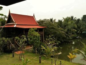 a building with a red roof next to a body of water at Baan Thai House in Phra Nakhon Si Ayutthaya